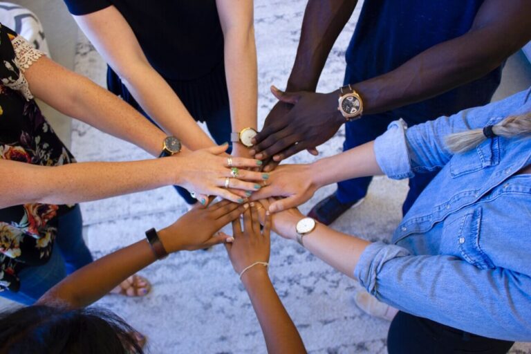 people putting their hands in a huddled circle