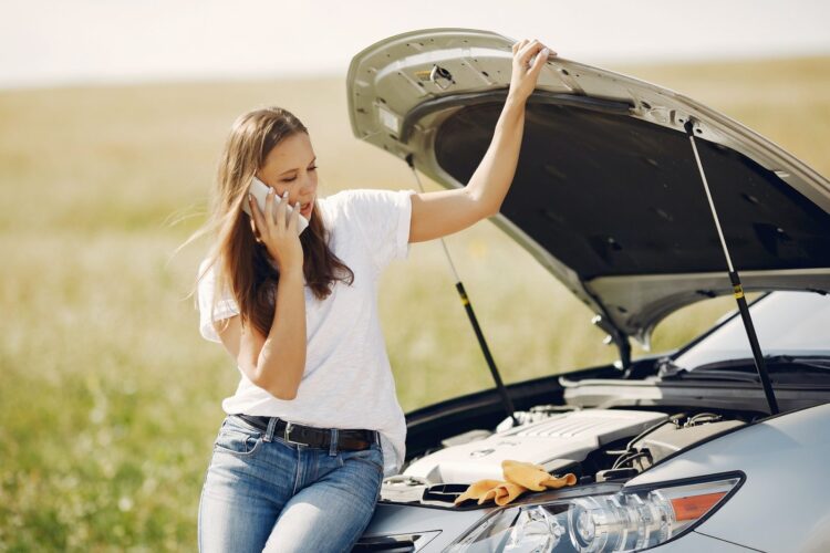 Woman on the phone with car with hood open