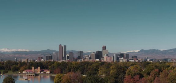 Denver skyline with mountain backdrop and City Park lake in the foreground