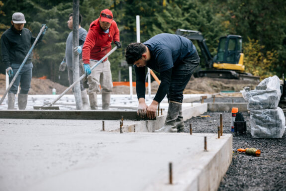 A team of hardworking men spreading, leveling, and pouring concrete